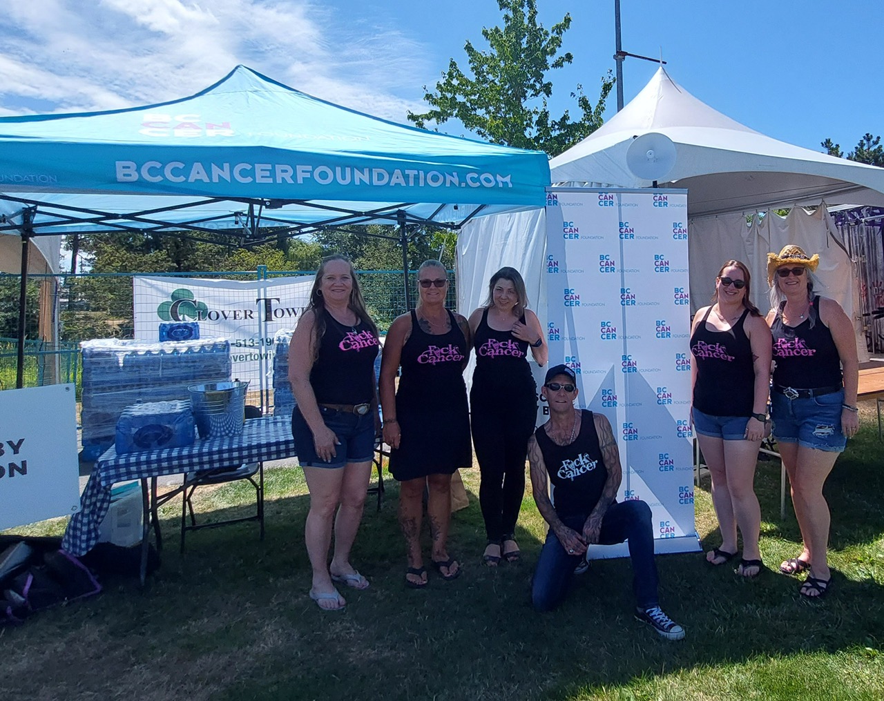 Six volunteers in FCK Cancer tanks at a BC Cancer Foundation tent